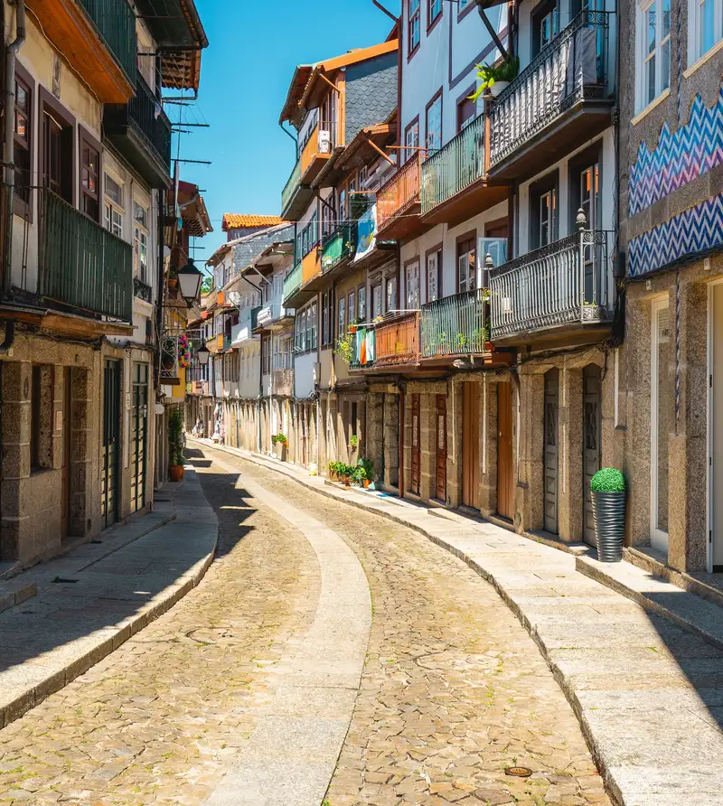 Rua de casas tradicionais com varandas de madeira no Vale do Ave